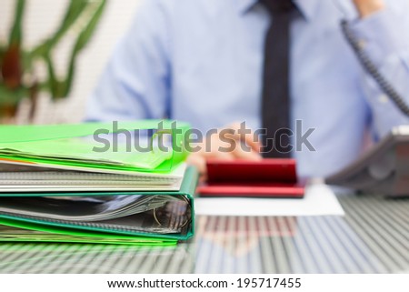 overloaded consultant in blur with stack of binders and speaking on phone