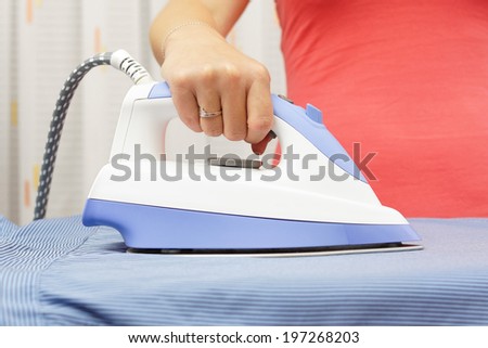 Woman\'s Hand Ironing Shirt On Ironing Board