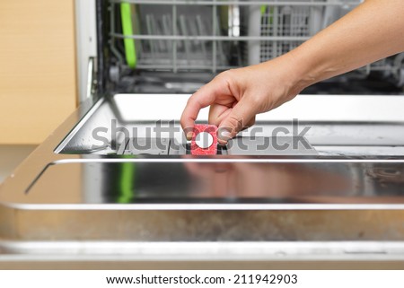 Woman putting tablet in dishwasher detergent box