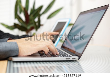 businessman in office  typing on keyboard with businesswoman using tablet pc in background