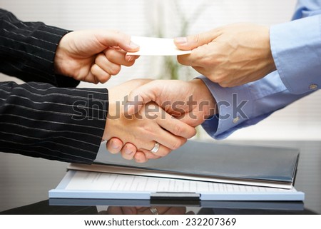 Business clients are exchanging business card  and handshaking after successful meeting
