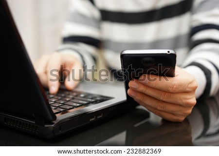 Teenager addicted to the Internet and Social Media using phone and laptop at the same time