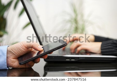 Man and woman on meeting  are using laptop computer and mobile smart phone