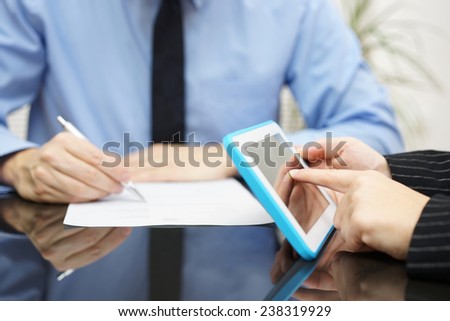 businesswoman is working with tablet pc and businessman is writing a document