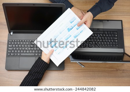 businesswoman on meeting passing report to partner , top view with laptop on desk