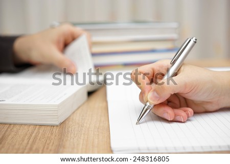 Male student is reading book, female is writing into notebook