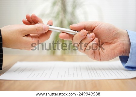 Woman is taking pen from businessman to sign the document