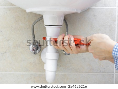 Plumber is r repairing sink In Bathroom