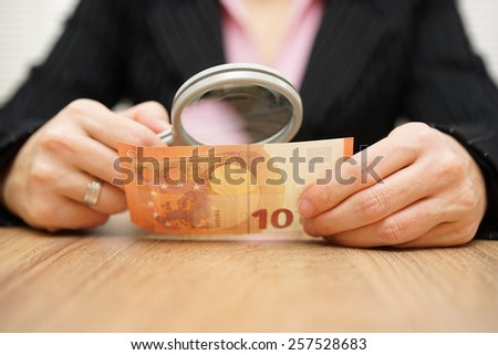 Businesswoman looking through a magnifying glass money. fraud concept