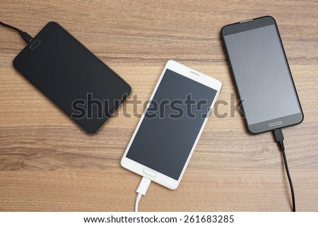 Mobile smart phones  charging on wooden desk