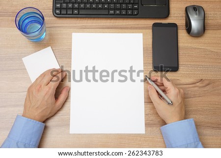 top view of desk with empty paper and man with pen in hand, ready for sample text