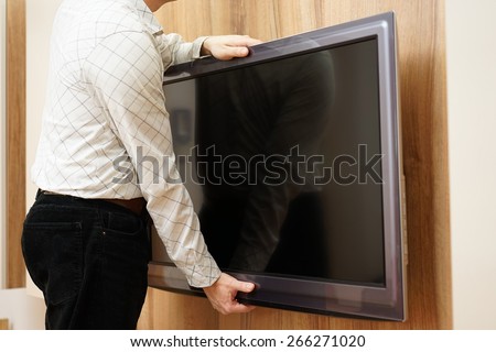 repairman gives television down from the wall in living room