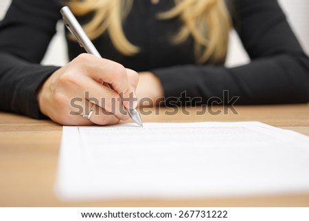 Woman with black shirt is signing legal document