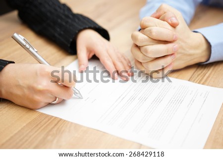 Man  with his hands clasped is waiting woman to sign the contract