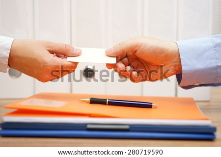 business partners are exchanging business cards over documents after meeting