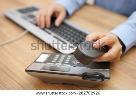 businessman hand picking up telephone receiver on business workplace