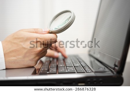 businessman is using  magnifying glass  on computer laptop. Internet search and protection concept