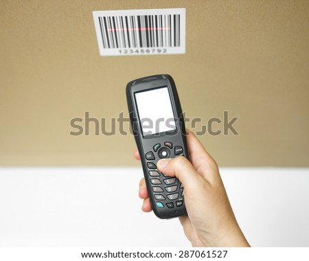 top view of woman hand holding bar code scanner with empty screen and reading code on box