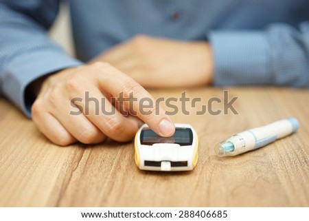 man testing glucose level with a digital glucometer, diabetes treatment