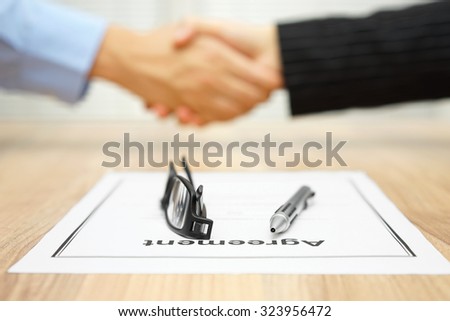Business people are handshaking over signed agreement,focus on  document