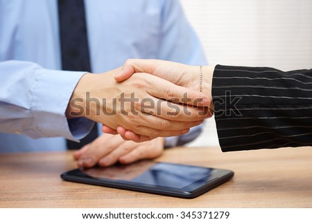 Businessman is  shaking hands with  partner after review of operations on the tablet pc