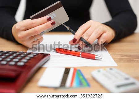 woman is cutting credit card or bank card with scissors over contract and other credit cards