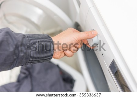Man is choosing Eco Program on the Washing Machine,concept of electricity savings