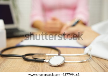doctor is writing prescription to patient, focus on stethoscope