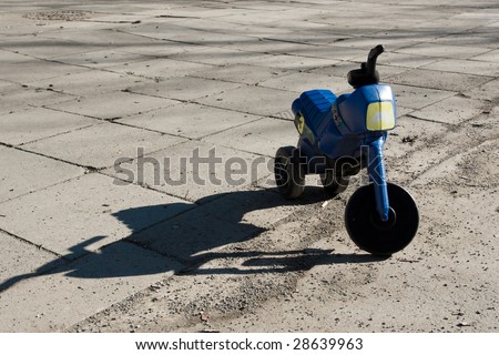A child\'s toy bike left in the concrete ground
