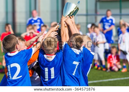 Young Soccer Players Holding Trophy. Boys Celebrating Soccer Football Championship. Winning team of sport tournament for kids children.