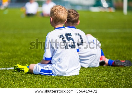 Young boys watching football match. Youth reserve players sitting on a soccer pitch ready to play football tournament.