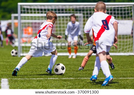 Training and football match between youth soccer teams. Young boys playing soccer game. Hard competition between players running and kicking soccer ball. Final game of football tournament for kids.