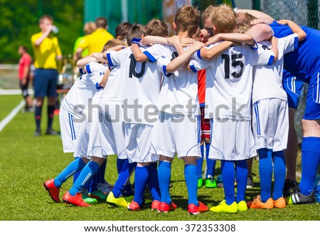 Coach giving young soccer team instructions. Youth soccer team together before final game. Football match for children. Boys group shout team, gathering. Coach briefing. Soccer football background.