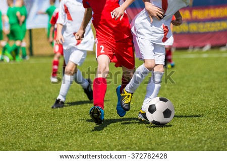 Young boys playing football soccer game. Running players in red and white uniforms
