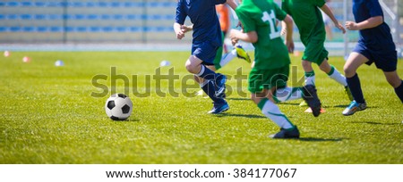 Boys play soccer match. Blue and green team on a sports field