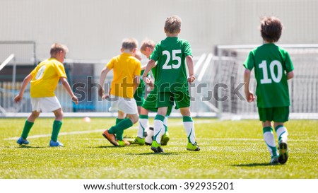 Boys play soccer match. Yellow and green team on a sports field