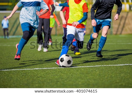 Football soccer game of youth teams. Running young players kicking soccer ball