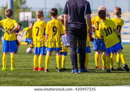 Coach and youth soccer reserve players watching football match. Coach giving young soccer team instructions.  Coach briefing. Soccer football background.
