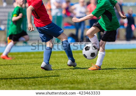 Young soccer football players playing match at sports field. Football soccer match for children. Kids playing soccer game tournament cup. Physical education classes at school.