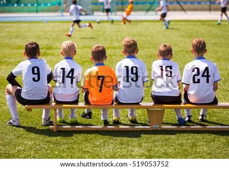 Young Football Players. Young Soccer Team Sitting on Wooden Bench. Soccer Match For Children. Young Boys Playing Tournament Soccer Match. Youth Soccer Club Footballers