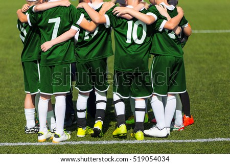 Sports team standing together on field. Football team motivated by coach. Youth soccer match
