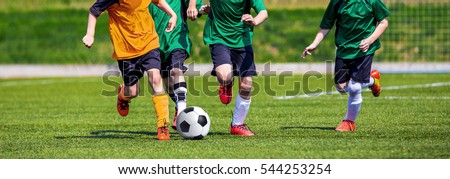 Running Youth Football Players. Kids Playing Football Soccer Game on Sports Field. Boys Play Soccer Match on Green Grass. Youth Soccer Tournament Teams Competition.