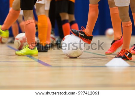 Football futsal training for children. Indoor soccer young player with a soccer ball in a sports hall. Sport background.