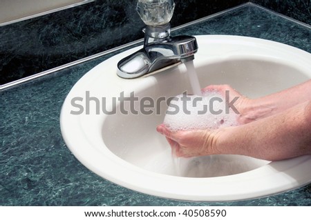 Hands full of suds under running water