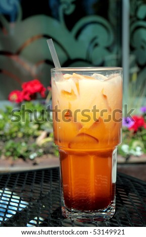 Tall refreshing glass of icy cold Thai iced tea with straw