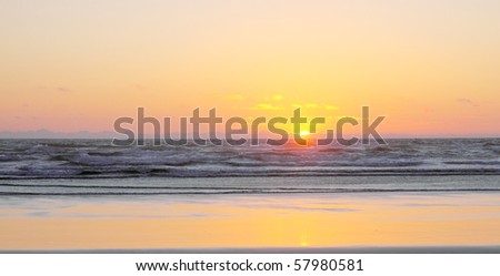 Beautiful pastel yellow, orange and coral sunset on sandy ocean beach