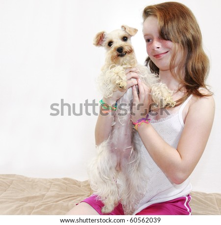 Beautiful freckled brunette female child holds cute white lap dog