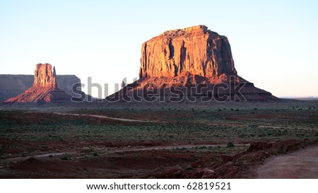 Monument Valley glows with golden and red colors as the setting sun shines on the sandstone monolithic rock formations
