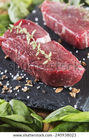 Raw beef tenderloin with spices over a blackboard