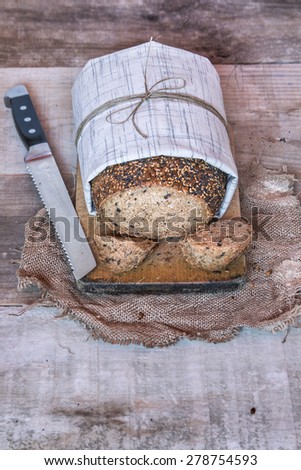 Loaf of bread with seeds wrapped in cloth over wooden background and copy space